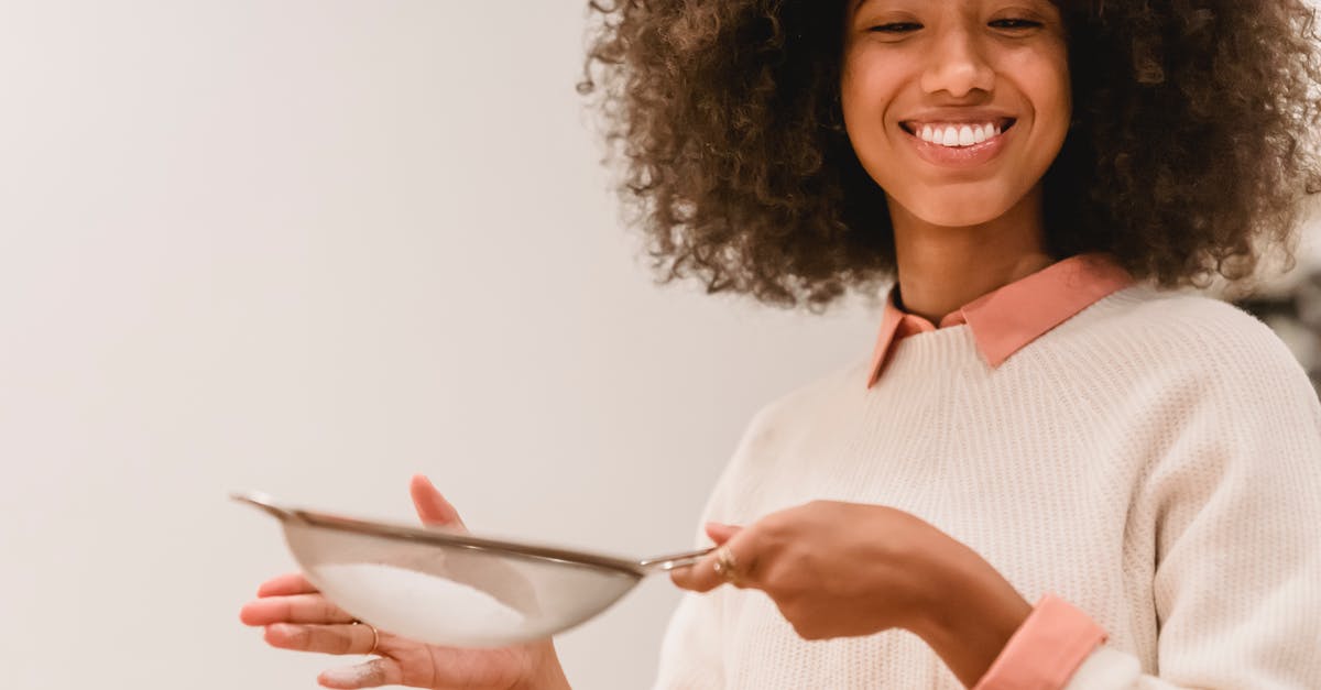Do I need to sift flour that is labeled sifted? - Cheerful black woman sifting flour Do I need to sift flour that is labeled sifted? - Cheerful black woman sifting flour