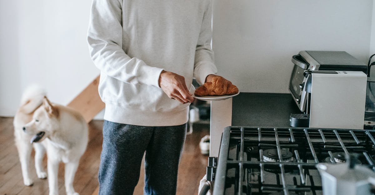 Do you know of a spinning plate for microwave? - Faceless man with croissant in hand standing in kitchen with cute dog Do you know of a spinning plate for microwave? - Faceless man with croissant in hand standing in kitchen with cute dog
