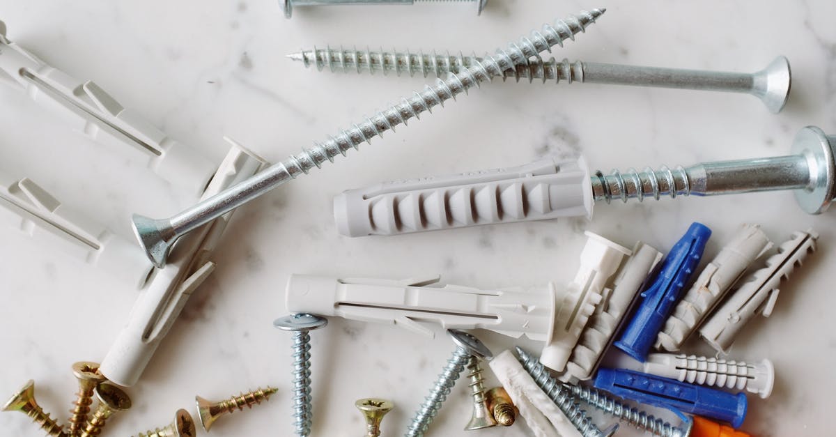 Does cast iron have a coating from the manufacturer? - Set of various multicolored plastic dowels with metal screws of different sizes placed on white marble table in modern workshop