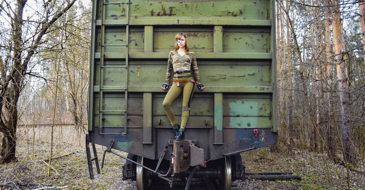 Does invisible mould exist? - Slim woman wearing modern camouflage outfit with eye patch standing on aged green train in woods Does invisible mould exist? - Slim woman wearing modern camouflage outfit with eye patch standing on aged green train in woods