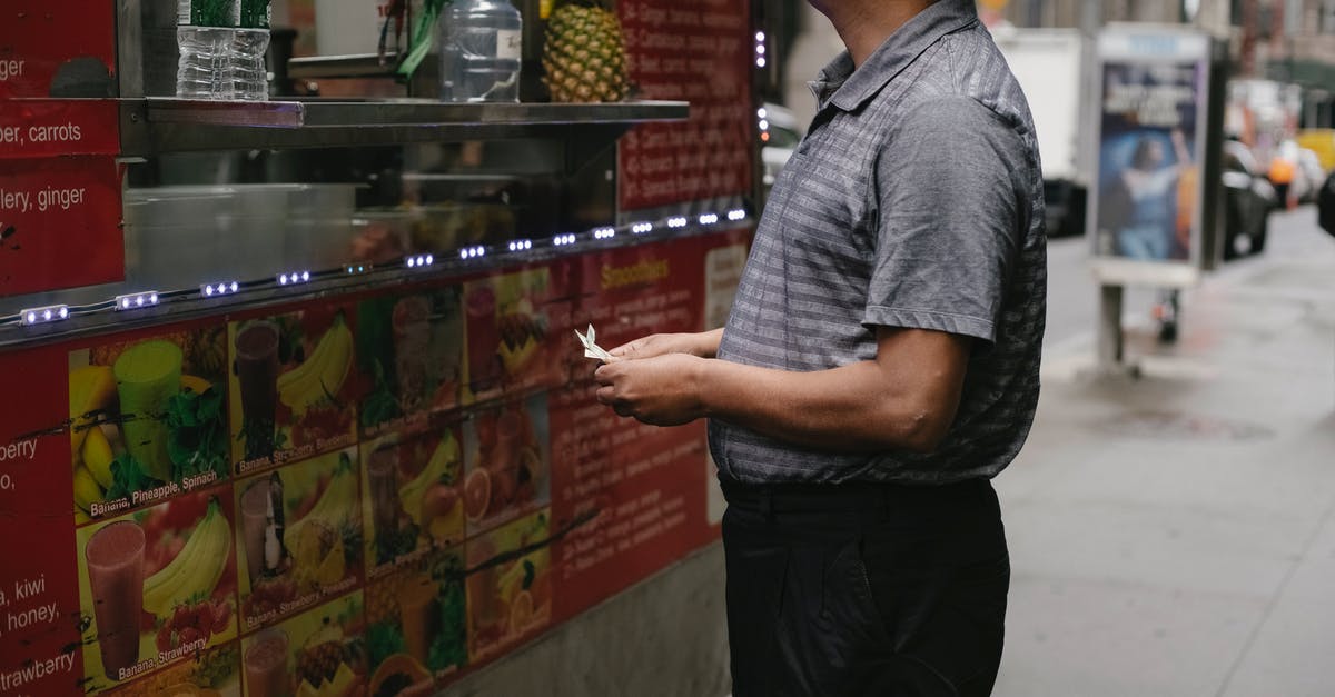 Does it harm juice if I store it in sub-zero temperatures? - Side view of tranquil man with banknotes buying street food at food truck with fruits on street in town Does it harm juice if I store it in sub-zero temperatures? - Side view of tranquil man with banknotes buying street food at food truck with fruits on street in town