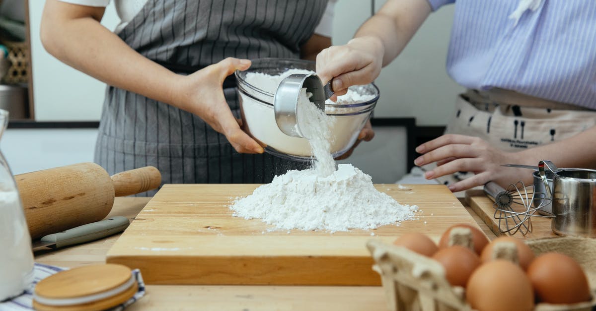 Does multi-cooker actually bake? - Crop anonymous woman in apron and young lady standing near counter and pouring flour on wooden cutting board in modern kitchen Does multi-cooker actually bake? - Crop anonymous woman in apron and young lady standing near counter and pouring flour on wooden cutting board in modern kitchen