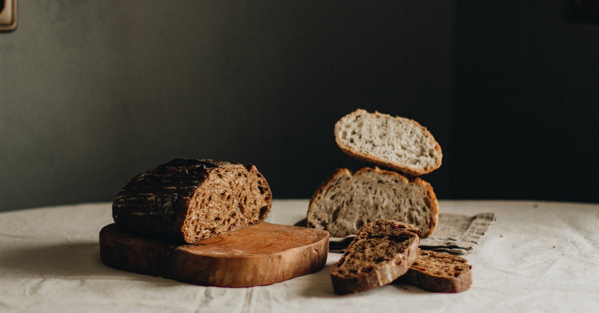 Does oven spring differ between white and sourdough breads? - Slices of tasty freshly baked sourdough bread placed on crumpled tablecloth on table with cutting board in light room on black background