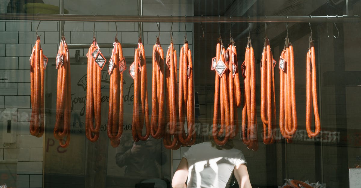 Does the vendors’ storage method affect shellfish quality? - Through glass back view of unrecognizable worker in white T shirt at meat preserving factory with long sausages hanging from metal rail in tiled room Does the vendors’ storage method affect shellfish quality? - Through glass back view of unrecognizable worker in white T shirt at meat preserving factory with long sausages hanging from metal rail in tiled room