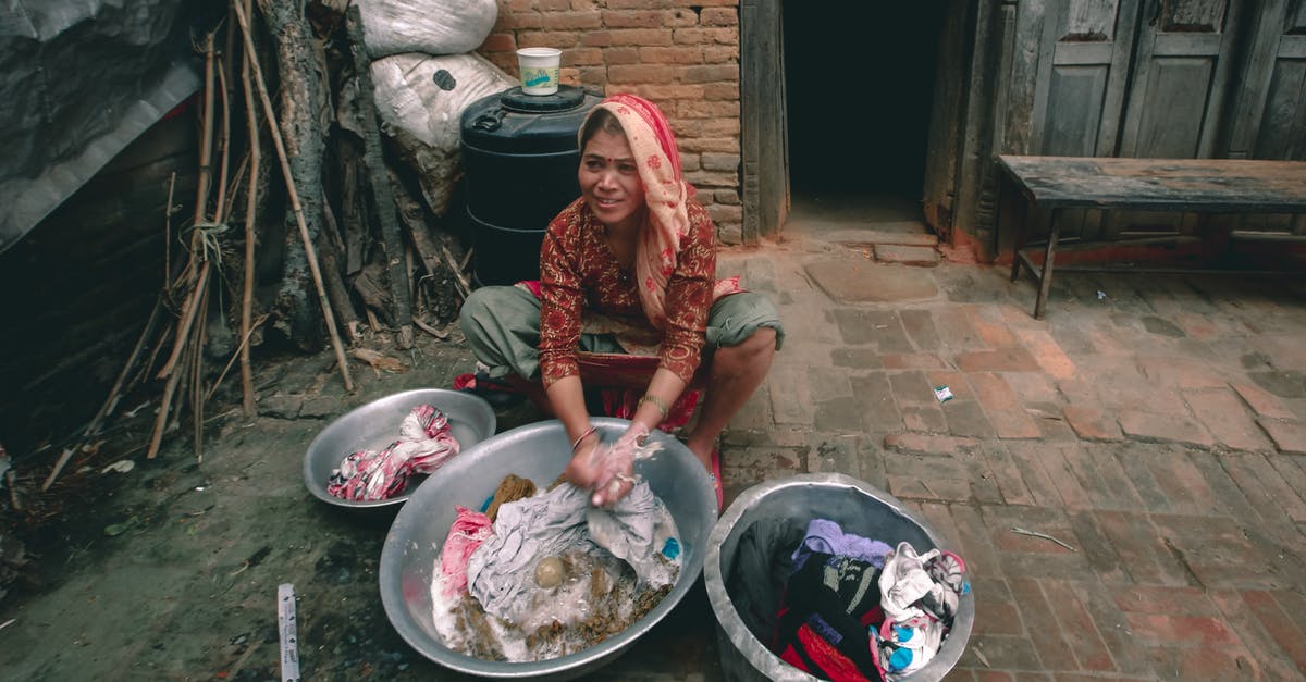Does washing kimchi with water reduce the sodium content much? - From above of content young ethnic female in traditional wear washing clothes in metal basins while looking away against old house Does washing kimchi with water reduce the sodium content much? - From above of content young ethnic female in traditional wear washing clothes in metal basins while looking away against old house
