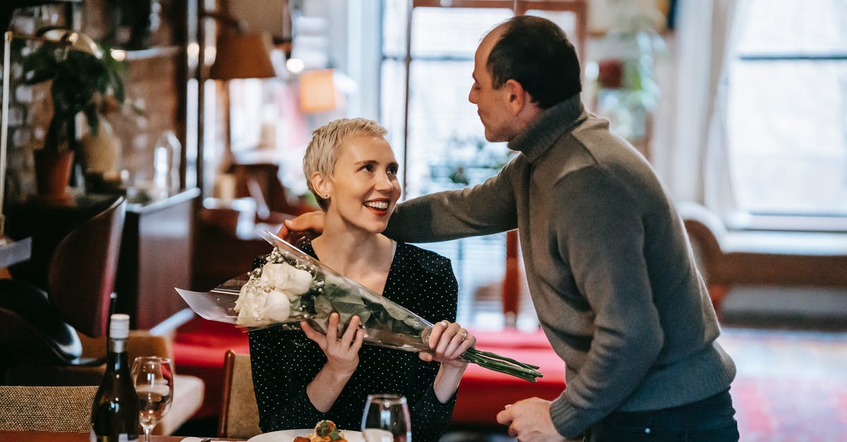 Does white wine have an expiry date? - Couple having romantic dinner while man giving bouquet of white roses to woman near table with plate with pasta near wine bottle and glasses while looking at each other Does white wine have an expiry date? - Couple having romantic dinner while man giving bouquet of white roses to woman near table with plate with pasta near wine bottle and glasses while looking at each other