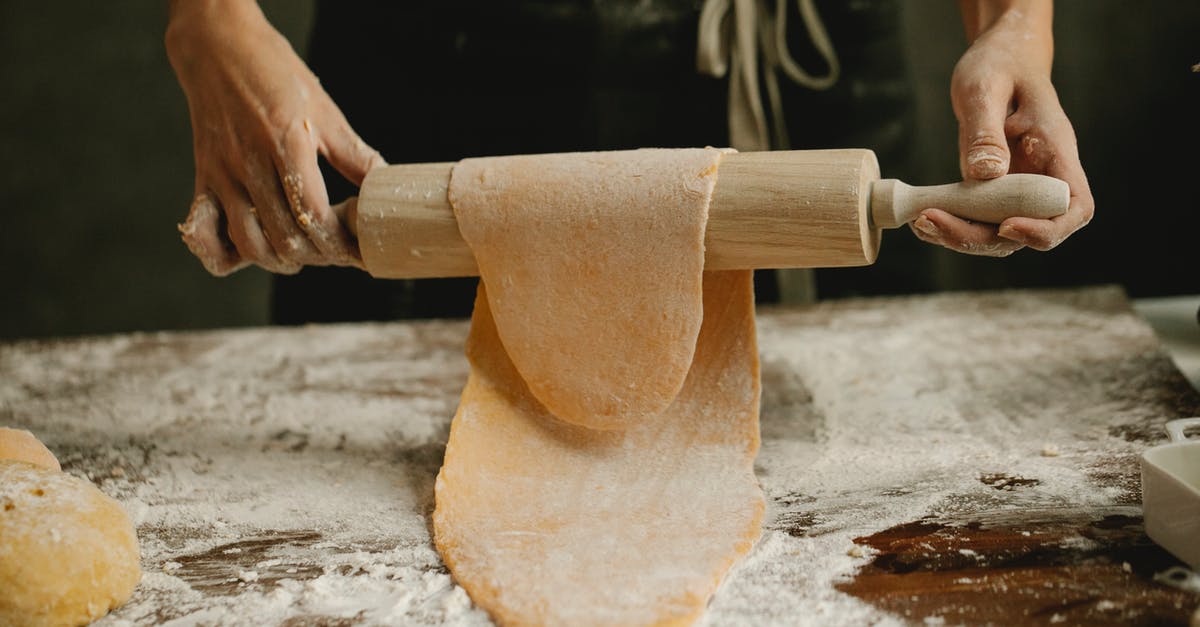 Dough is super springy and sticky. Tears while stretching - Unrecognizable female stretching soft egg dough on rolling pin while making homemade pasta in kitchen Dough is super springy and sticky. Tears while stretching - Unrecognizable female stretching soft egg dough on rolling pin while making homemade pasta in kitchen