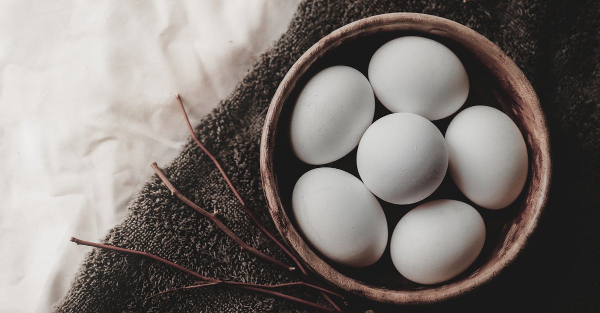 Drying whole, small fish at home - Top view of chicken eggs in wicker bowl placed near twigs on gray towel