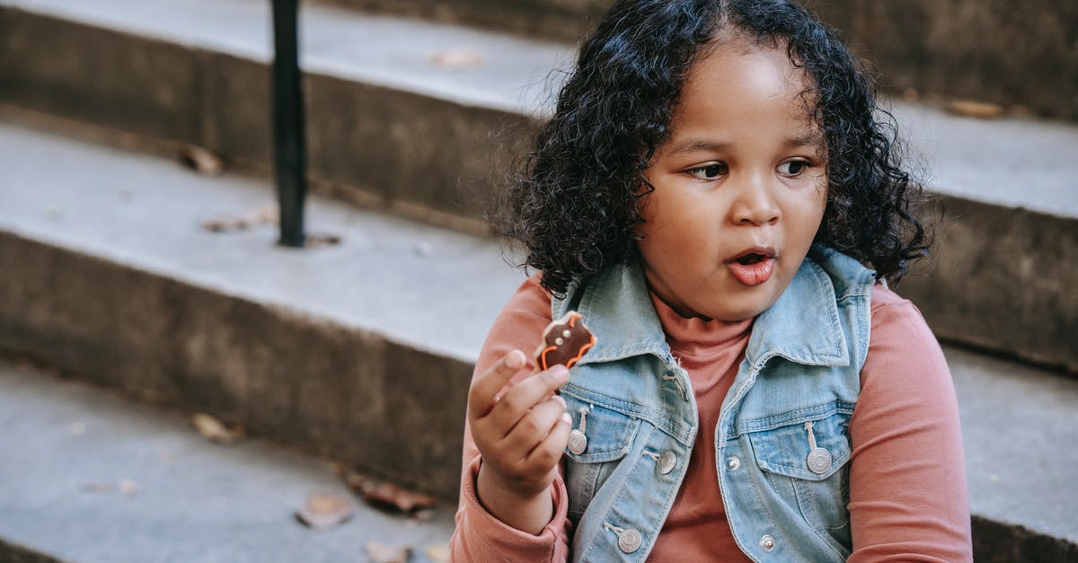Eating cookie dough - Black girl eating bat shaped cookie Eating cookie dough - Black girl eating bat shaped cookie