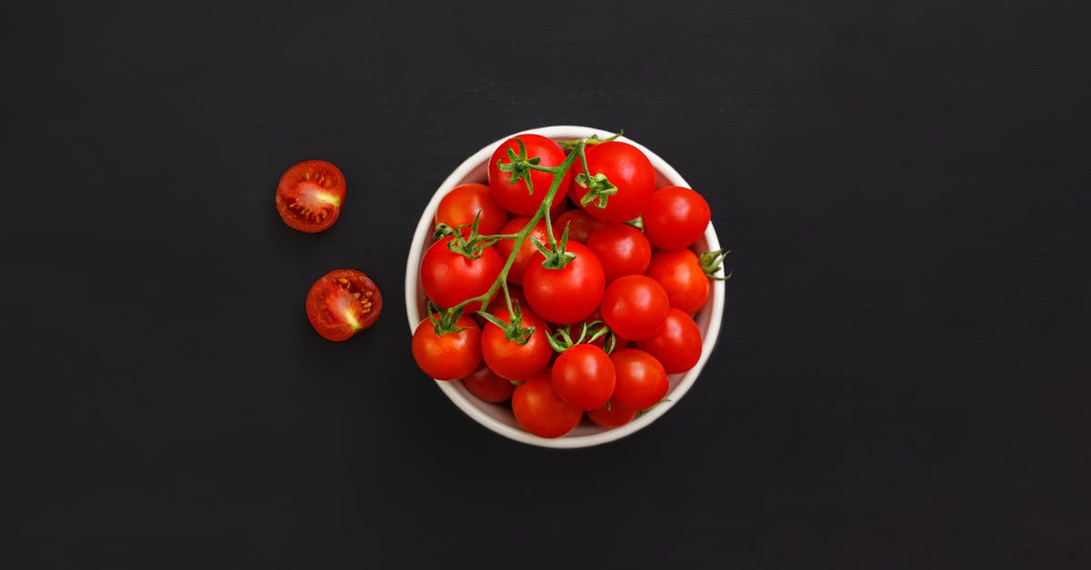 Eating dehydrated uncooked red potato - Bowl with ripe cherry tomatoes on black background Eating dehydrated uncooked red potato - Bowl with ripe cherry tomatoes on black background