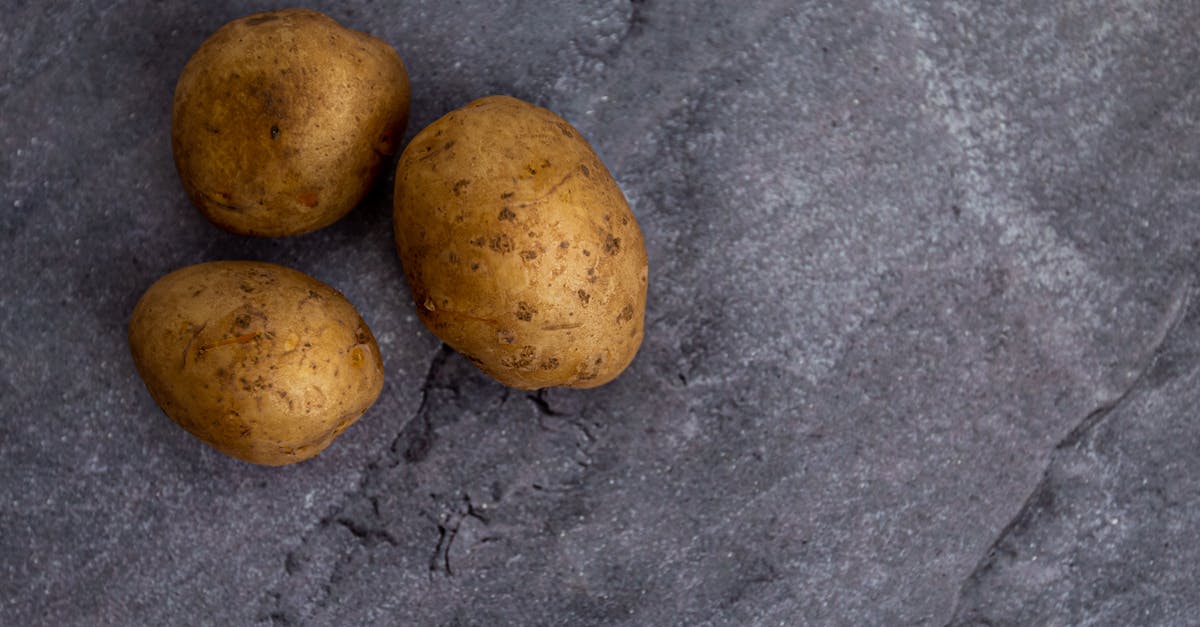 Eating dehydrated uncooked red potato - Top view of whole unpeeled potatoes placed on rough gray marble table in kitchen Eating dehydrated uncooked red potato - Top view of whole unpeeled potatoes placed on rough gray marble table in kitchen