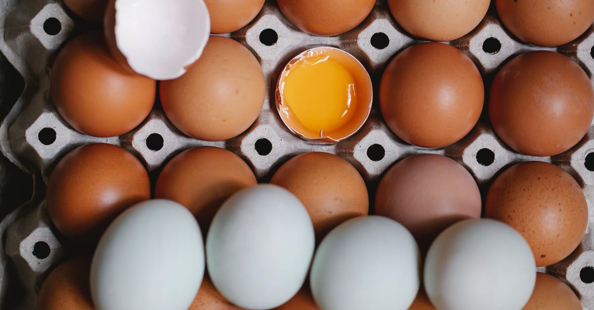 Effect of adding whole egg or yolk to filo pastry? - Top view of yolk in broken eggshell among whole eggs in carton container Effect of adding whole egg or yolk to filo pastry? - Top view of yolk in broken eggshell among whole eggs in carton container