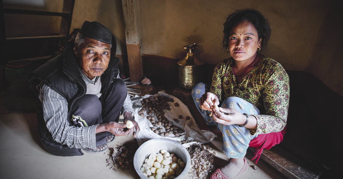 Efficient method to peel raw potatoes - High angle of young and elderly ethnic female in ornamental apparel peeling small potatoes while looking at camera at home Efficient method to peel raw potatoes - High angle of young and elderly ethnic female in ornamental apparel peeling small potatoes while looking at camera at home