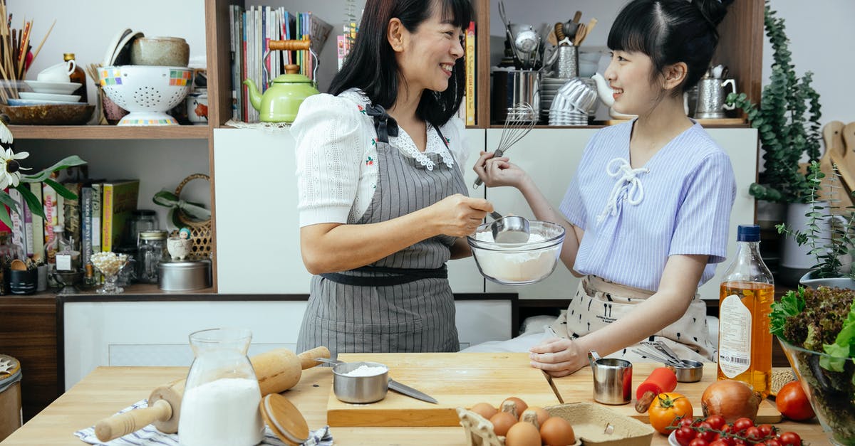 Egg and gluten free custard ideas? - Happy Asian mother wearing apron and daughter standing near wooden counter with ingredients while discussing recipe of pizza Egg and gluten free custard ideas? - Happy Asian mother wearing apron and daughter standing near wooden counter with ingredients while discussing recipe of pizza