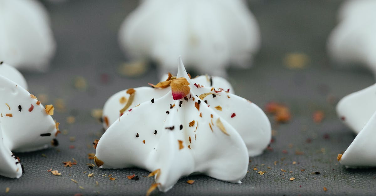 Egg temperature for meringue - Closeup of uncooked white meringue dessert with mix of dry spices on top on baking pan Egg temperature for meringue - Closeup of uncooked white meringue dessert with mix of dry spices on top on baking pan
