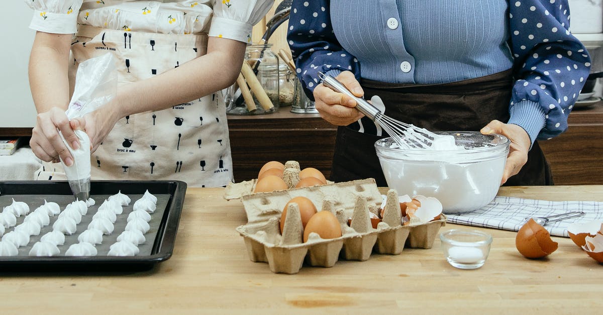 Egg temperature for meringue - Crop anonymous woman with teen preparing mixture from egg whites for sweet pastries at table in house Egg temperature for meringue - Crop anonymous woman with teen preparing mixture from egg whites for sweet pastries at table in house