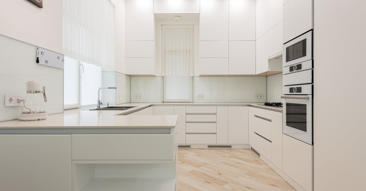 Electric Steam Cooker - Interior of light kitchen with white cabinets and kettle near sink placed against trendy oven and modern appliances in apartment Electric Steam Cooker - Interior of light kitchen with white cabinets and kettle near sink placed against trendy oven and modern appliances in apartment