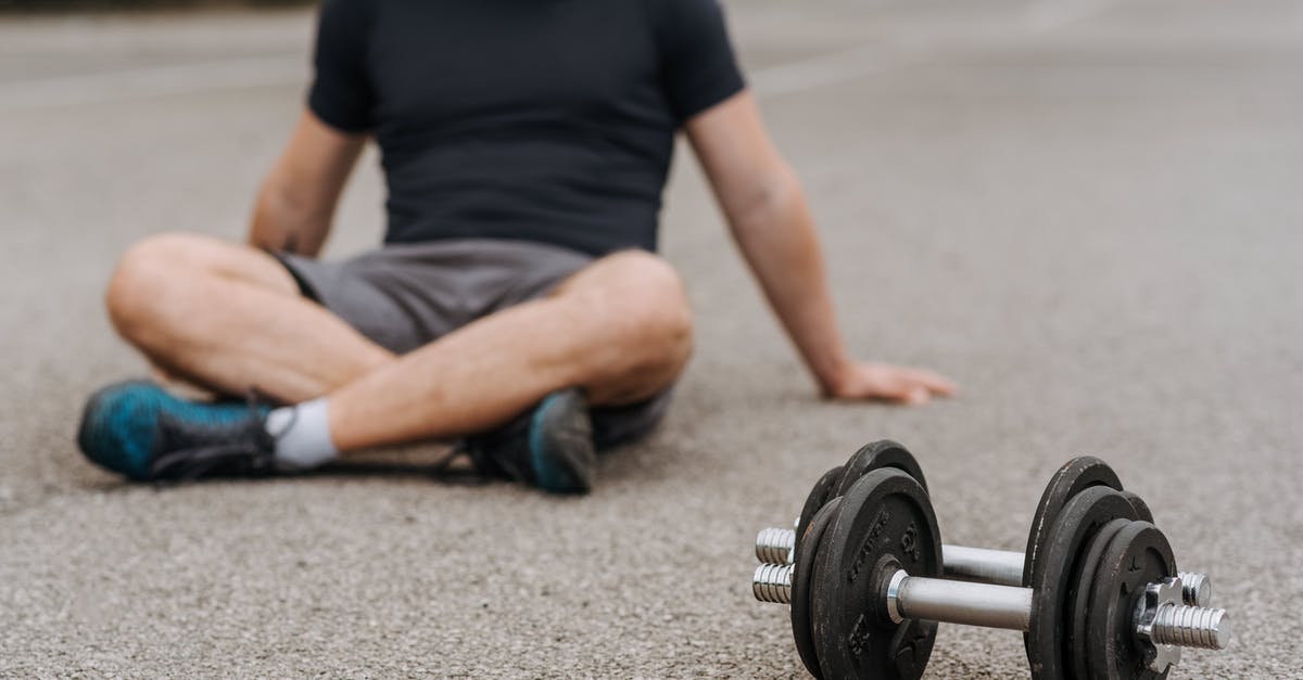 Energy bar is too soft - Crop sportsman resting on road near dumbbells after working out Energy bar is too soft - Crop sportsman resting on road near dumbbells after working out