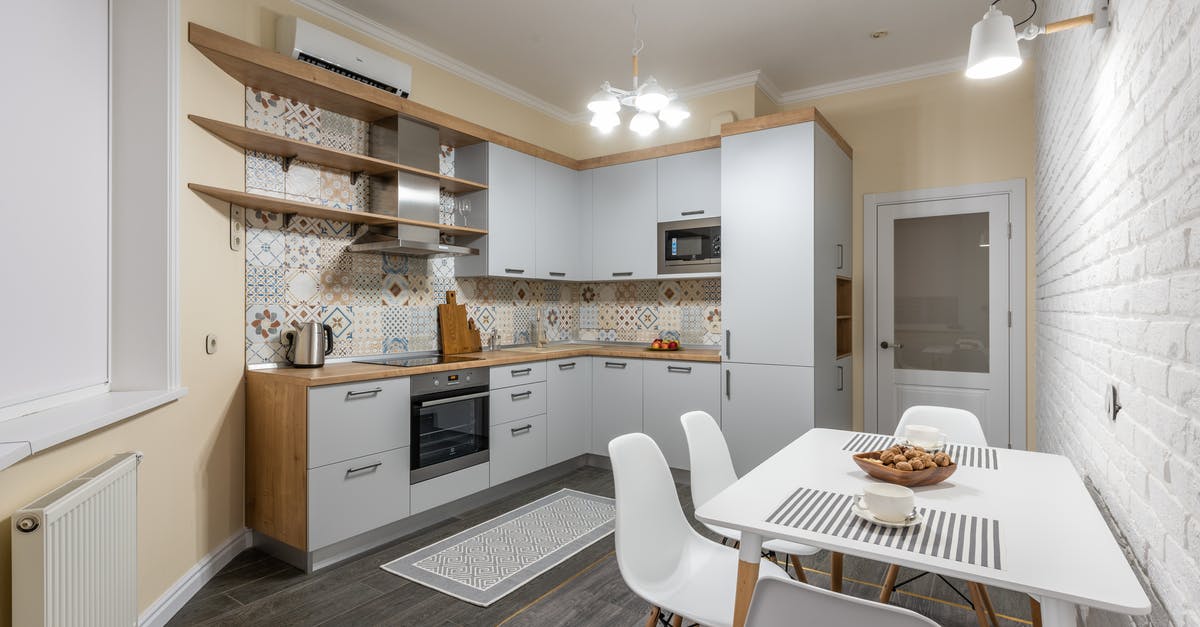Energy efficiency of microwave and electric kettle for heating water - Modern kitchen with electric appliances and radiator against table with tasty biscuits and cups illuminated by bright chandelier Energy efficiency of microwave and electric kettle for heating water - Modern kitchen with electric appliances and radiator against table with tasty biscuits and cups illuminated by bright chandelier