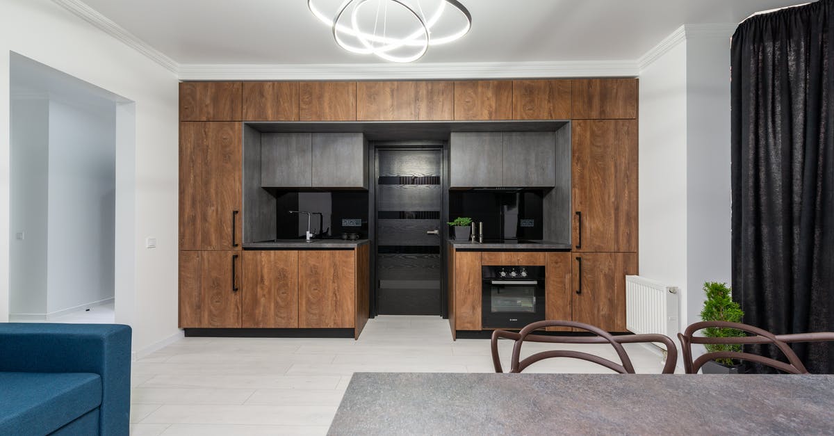 Energy usage of an oven - Creative design of kitchen with cupboards and built in oven against table and sofa in house with geometric lamp Energy usage of an oven - Creative design of kitchen with cupboards and built in oven against table and sofa in house with geometric lamp