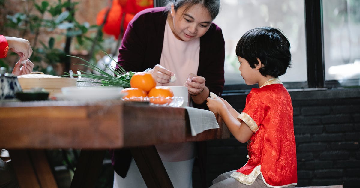 Explaining raising dough - Asian grandmother helping boy to cook traditional food Explaining raising dough - Asian grandmother helping boy to cook traditional food