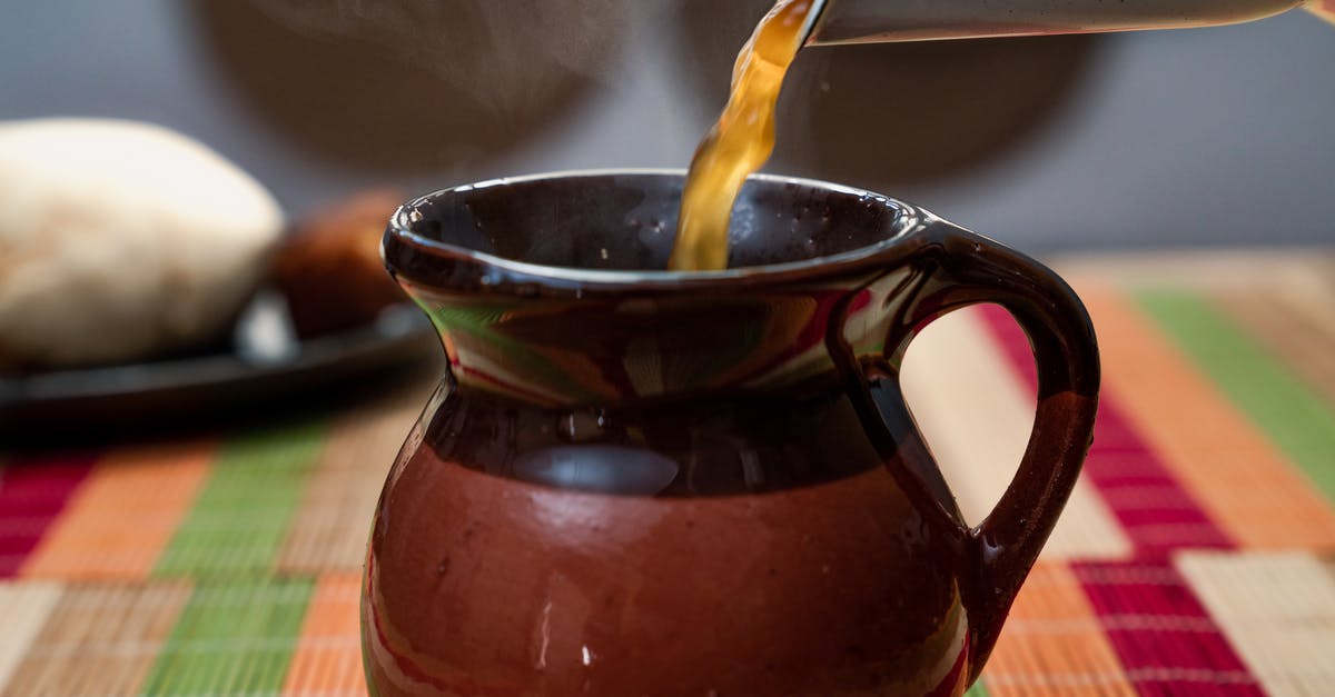 Filling a hot Kettle - Hot bouillon poured from teapot into clay jug Filling a hot Kettle - Hot bouillon poured from teapot into clay jug