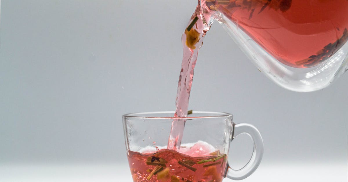Filling a hot Kettle - Herbal tea with dried leaves and fruit pouring from glass teapot into cup Filling a hot Kettle - Herbal tea with dried leaves and fruit pouring from glass teapot into cup