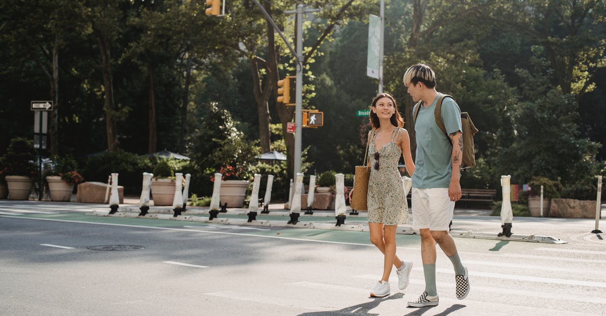 First slicing, then cooking, or the other way around? - Full body of happy young girlfriend carrying bag while walking on asphalt crosswalk with boyfriend First slicing, then cooking, or the other way around? - Full body of happy young girlfriend carrying bag while walking on asphalt crosswalk with boyfriend