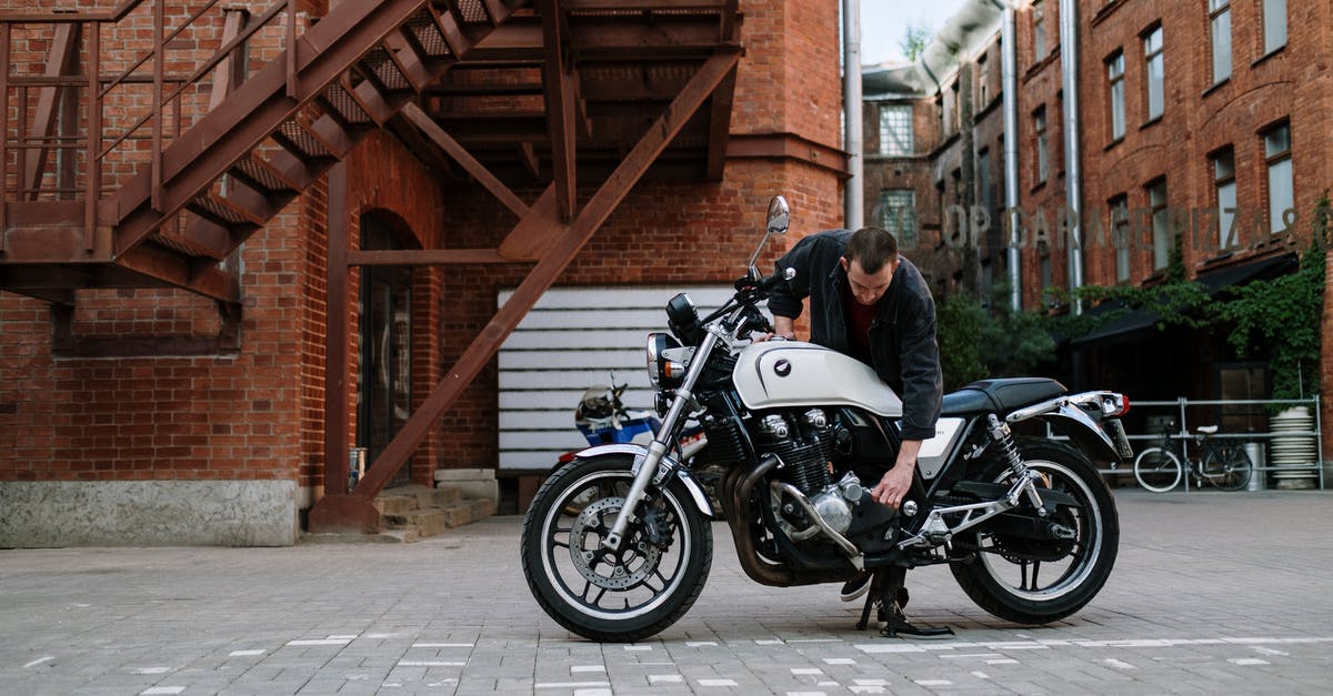 Fixing a Brownie Brick - Man Fixing Motorcycle Parked Beside Brick Building Fixing a Brownie Brick - Man Fixing Motorcycle Parked Beside Brick Building