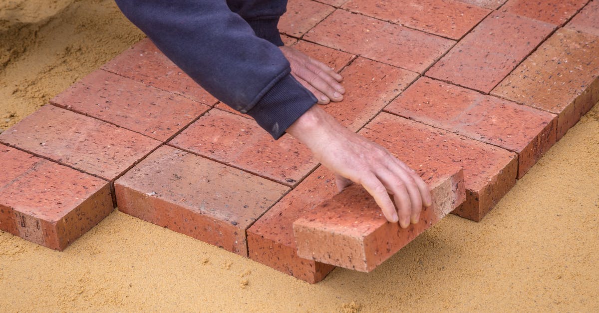 Fixing a Brownie Brick - Crop faceless man laying bricks on ground Fixing a Brownie Brick - Crop faceless man laying bricks on ground