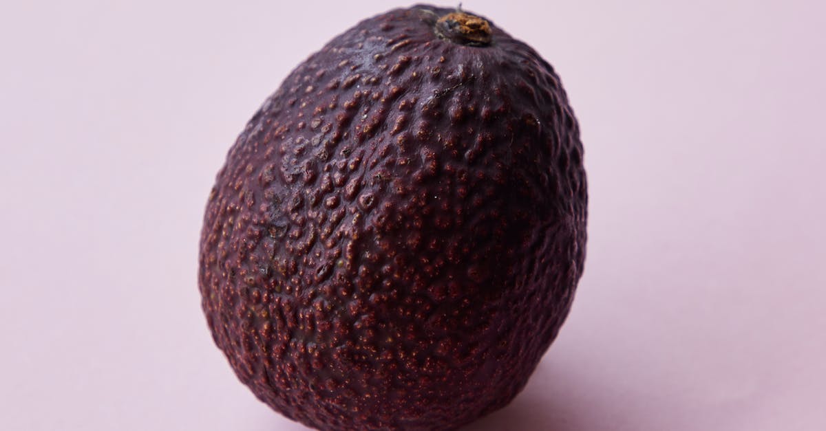 Flavor in avocadoes gone forever? - Closeup of ripe big unpeeled whole brown avocado tree fruit on purple background Flavor in avocadoes gone forever? - Closeup of ripe big unpeeled whole brown avocado tree fruit on purple background