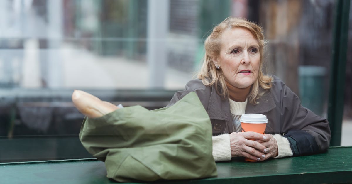 Flies in my bag of bread - bad bread? - Contemplative senior female with disposable cup of hot drink and baguette in bag looking away at cafe counter