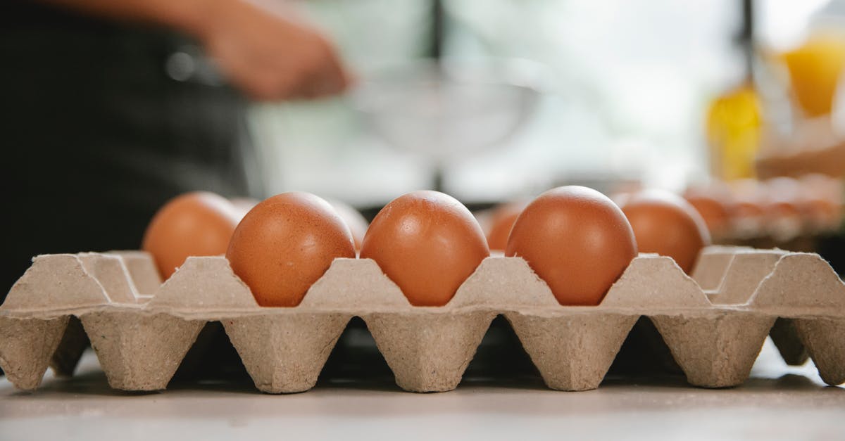 Flour protein and browning - Eggs in carton container placed on table near chef cooking food in kitchen Flour protein and browning - Eggs in carton container placed on table near chef cooking food in kitchen