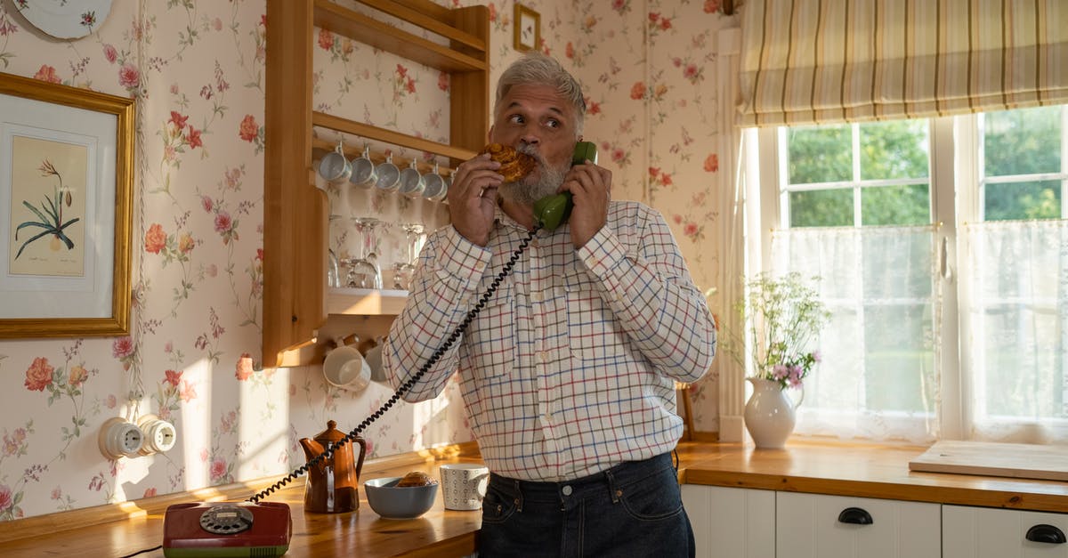 Food-safe rotary evaporator grease - Senior Man Talking on Landline Phone and Eating Cinnamon Bun in Old-Fashioned Kitchen Food-safe rotary evaporator grease - Senior Man Talking on Landline Phone and Eating Cinnamon Bun in Old-Fashioned Kitchen