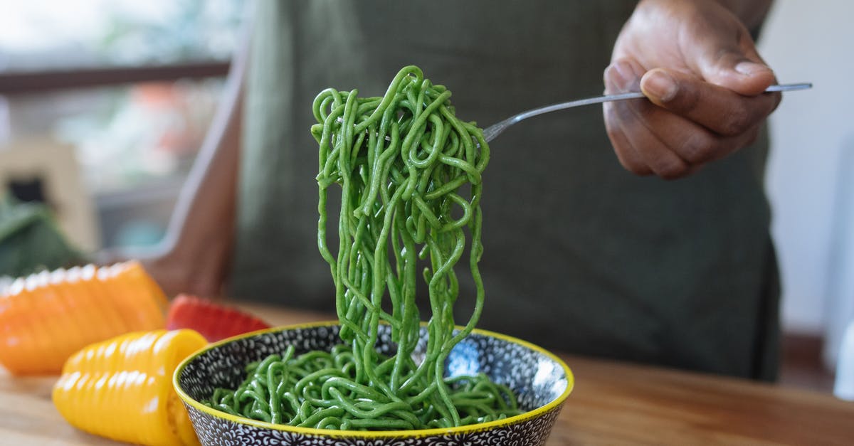 Fresh pasta noodles in lasagna - Person Holding Stainless Steel Fork With Green Noodles in Blue Ceramic Bowl Fresh pasta noodles in lasagna - Person Holding Stainless Steel Fork With Green Noodles in Blue Ceramic Bowl