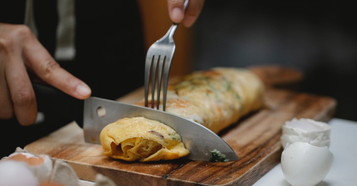 fried garam masala tastes watery - Crop anonymous cook with knife and fork cutting yummy hot egg roll on wooden board fried garam masala tastes watery - Crop anonymous cook with knife and fork cutting yummy hot egg roll on wooden board