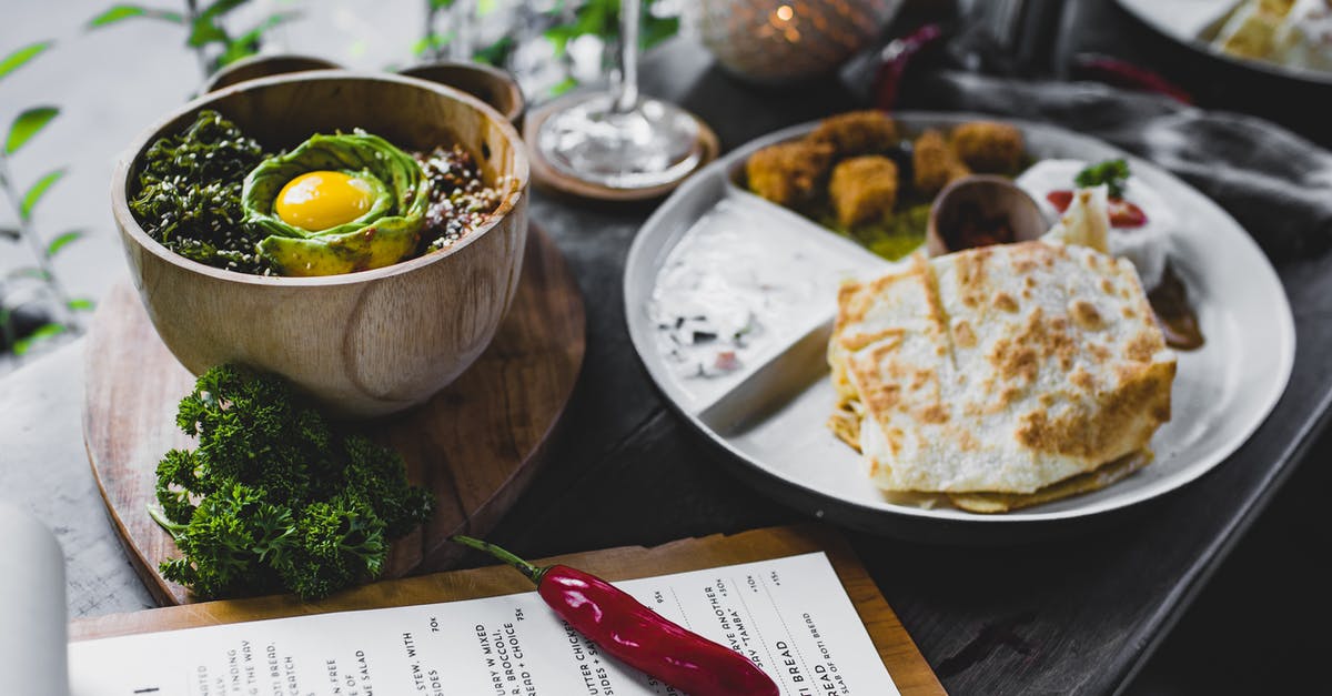 From a food safety perspective, what's the difference between a dish I ate in and rinsed off afterward vs. a dish with food that I didn't eat in? - High angle of plate with roti bread and different Asian snacks placed on table with bowl of exotic food served with eggplant and avocado