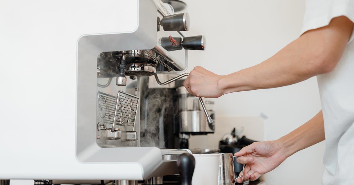 Frothing Milk By Hand - Side view crop anonymous barista in white shirt preparing to steam milk in frothing pitcher using professional coffee machine steam wand Frothing Milk By Hand - Side view crop anonymous barista in white shirt preparing to steam milk in frothing pitcher using professional coffee machine steam wand