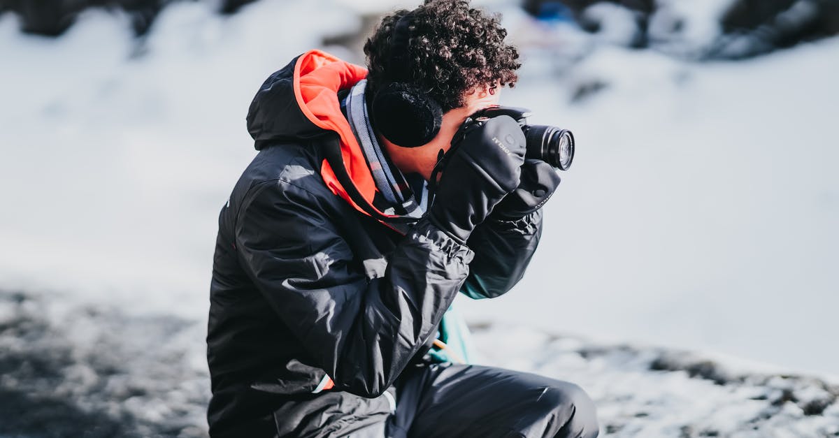 frozen chips always take longer - Side view of male photographer with curly hair in gloves squatting near snowy ground while taking pictures on camera of frozen scenery frozen chips always take longer - Side view of male photographer with curly hair in gloves squatting near snowy ground while taking pictures on camera of frozen scenery