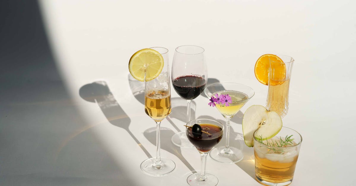 Fruit that has been mistaken as olive fruit? - High angle of crystal glasses filled with champagne red wine Manhattan with olive on toothpick martini near pear calvados in white studio Fruit that has been mistaken as olive fruit? - High angle of crystal glasses filled with champagne red wine Manhattan with olive on toothpick martini near pear calvados in white studio