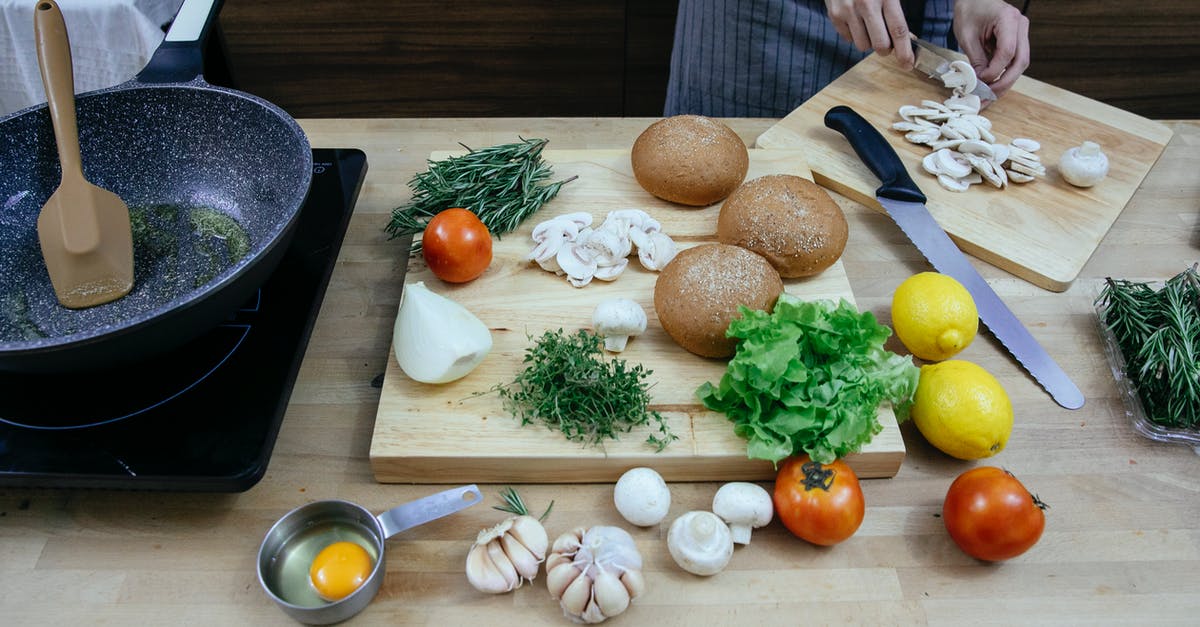 Fry onions and garlic before adding to the sauce? - Crop anonymous female chef wearing apron cutting fresh mushrooms while standing at table with scattered ripe vegetables including onions tomatoes and potatoes in modern kitchen Fry onions and garlic before adding to the sauce? - Crop anonymous female chef wearing apron cutting fresh mushrooms while standing at table with scattered ripe vegetables including onions tomatoes and potatoes in modern kitchen