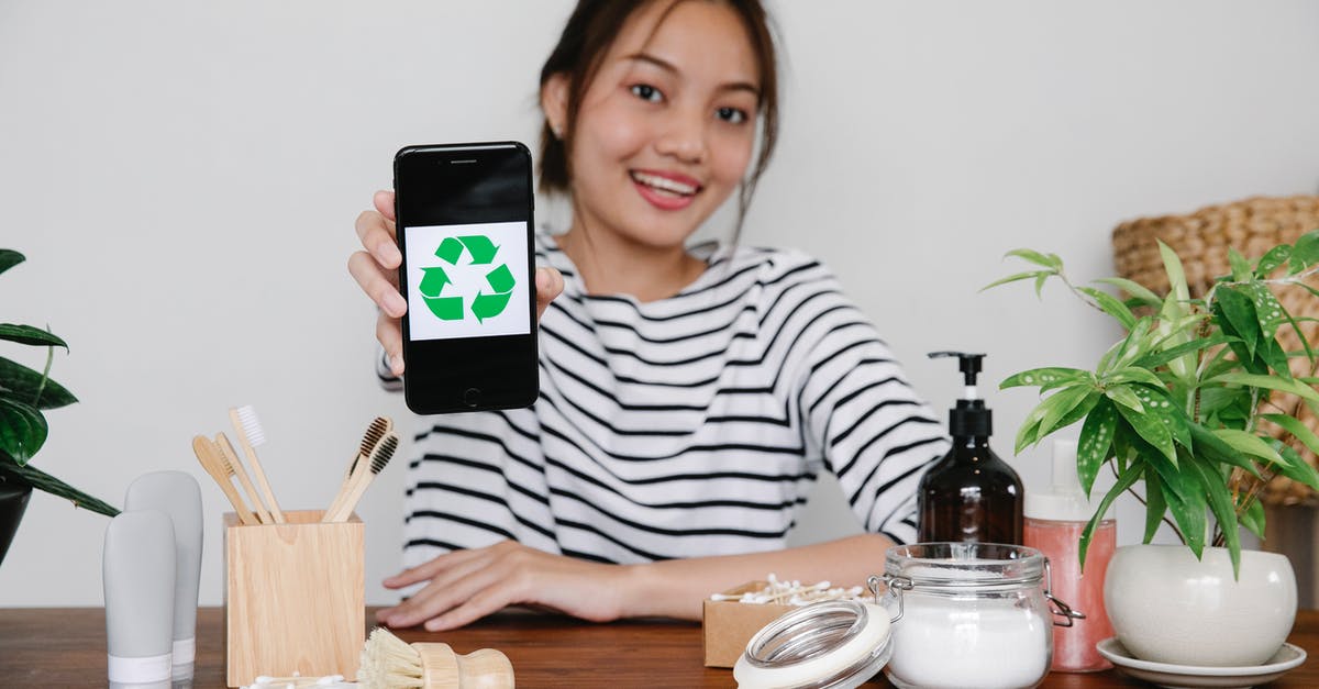 Funnel-like device for putting non-liquids into a whipped cream dispenser? - Smiling Asian woman demonstrating recycling symbol on smartphone while sitting at table with eco friendly cosmetic products and looking at camera Funnel-like device for putting non-liquids into a whipped cream dispenser? - Smiling Asian woman demonstrating recycling symbol on smartphone while sitting at table with eco friendly cosmetic products and looking at camera
