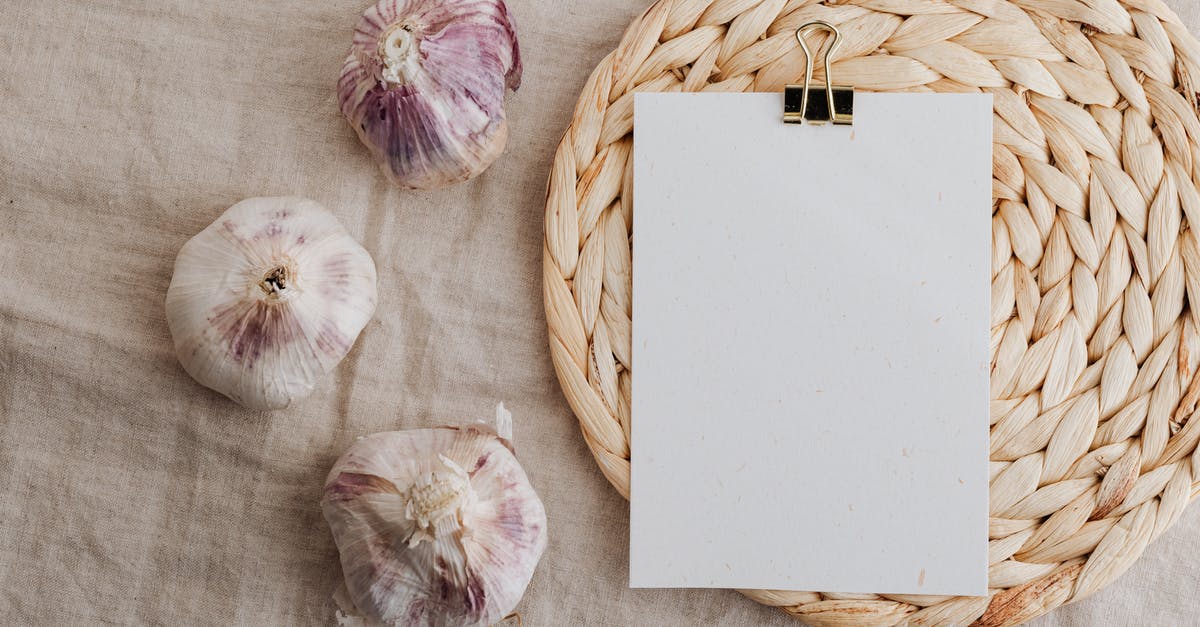 Garlic clove has turned to a firm jelly texture - Garlic and blank paper over wicker placemat on white tablecloth Garlic clove has turned to a firm jelly texture - Garlic and blank paper over wicker placemat on white tablecloth