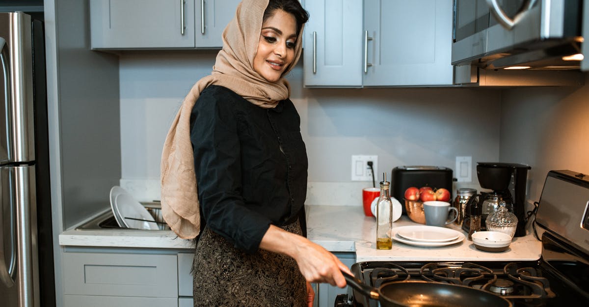 Gas Grill vs. Burner for Paella - Content Arabic woman with frying pan in modern kitchen Gas Grill vs. Burner for Paella - Content Arabic woman with frying pan in modern kitchen
