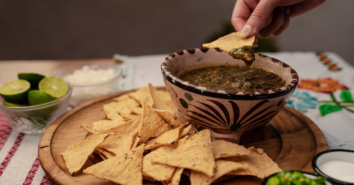 Getting crispy banana chips - A Person Dipping Chips on Salsa Getting crispy banana chips - A Person Dipping Chips on Salsa