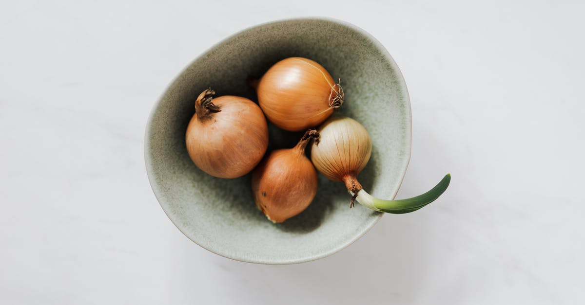 Getting onion/garlic smell out of rice cooker - Top view of light green bowl with unpeeled raw organic yellow onion bulbs and one regrowing onion placed on white marble tabletop Getting onion/garlic smell out of rice cooker - Top view of light green bowl with unpeeled raw organic yellow onion bulbs and one regrowing onion placed on white marble tabletop