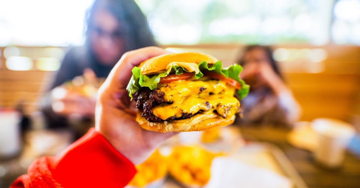 Getting the lighter fluid taste out of burgers, after the fact - Crop anonymous person sitting at table and reaching out hand and demonstrating tasty cheeseburger in cafe in daylight Getting the lighter fluid taste out of burgers, after the fact - Crop anonymous person sitting at table and reaching out hand and demonstrating tasty cheeseburger in cafe in daylight