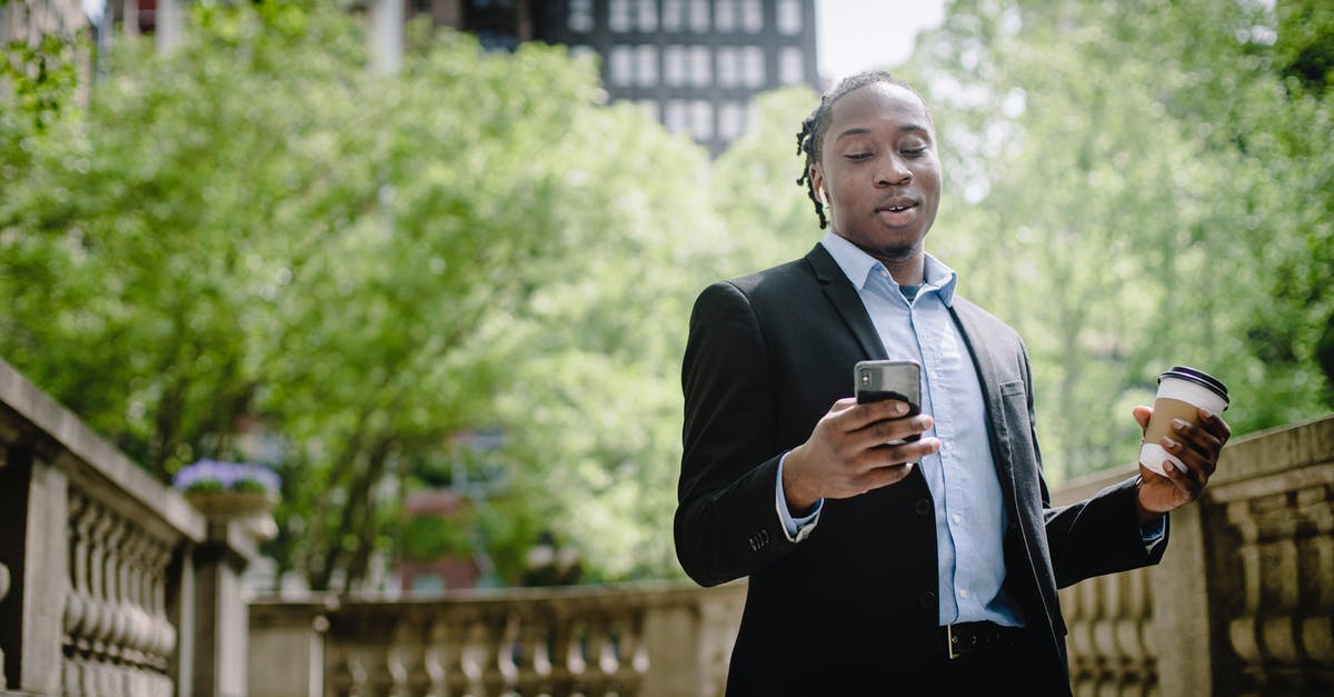Good programmable coffee urn solution - Positive young black man with smartphone and takeaway coffee in city park Good programmable coffee urn solution - Positive young black man with smartphone and takeaway coffee in city park