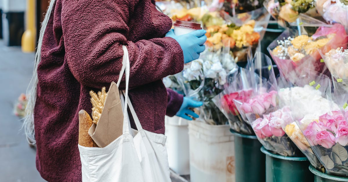 Good ways to store coffee? - Woman with paper cup of coffee buying flowers on street Good ways to store coffee? - Woman with paper cup of coffee buying flowers on street