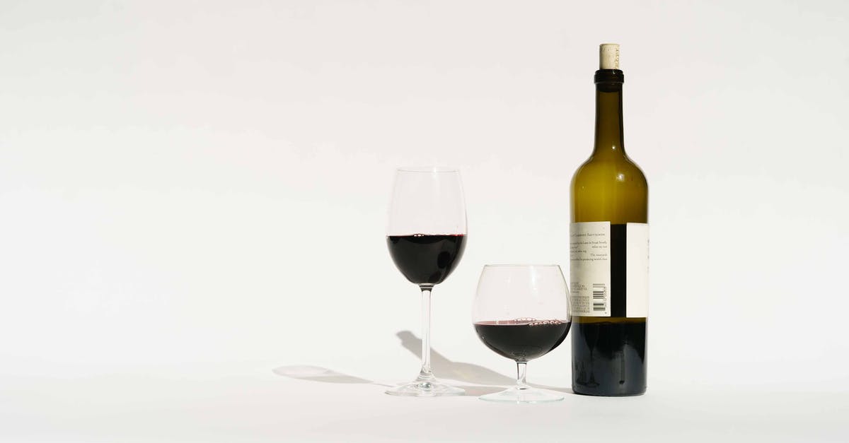 Grape vinegar vs wine vinegar - Red wine made from dark colored grape varieties in bottle and glasses placed in white studio Grape vinegar vs wine vinegar - Red wine made from dark colored grape varieties in bottle and glasses placed in white studio